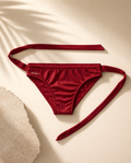 Alt Maré The Luxe men's swim briefs in deep red, tie-waist detail flat lay with palm shadow