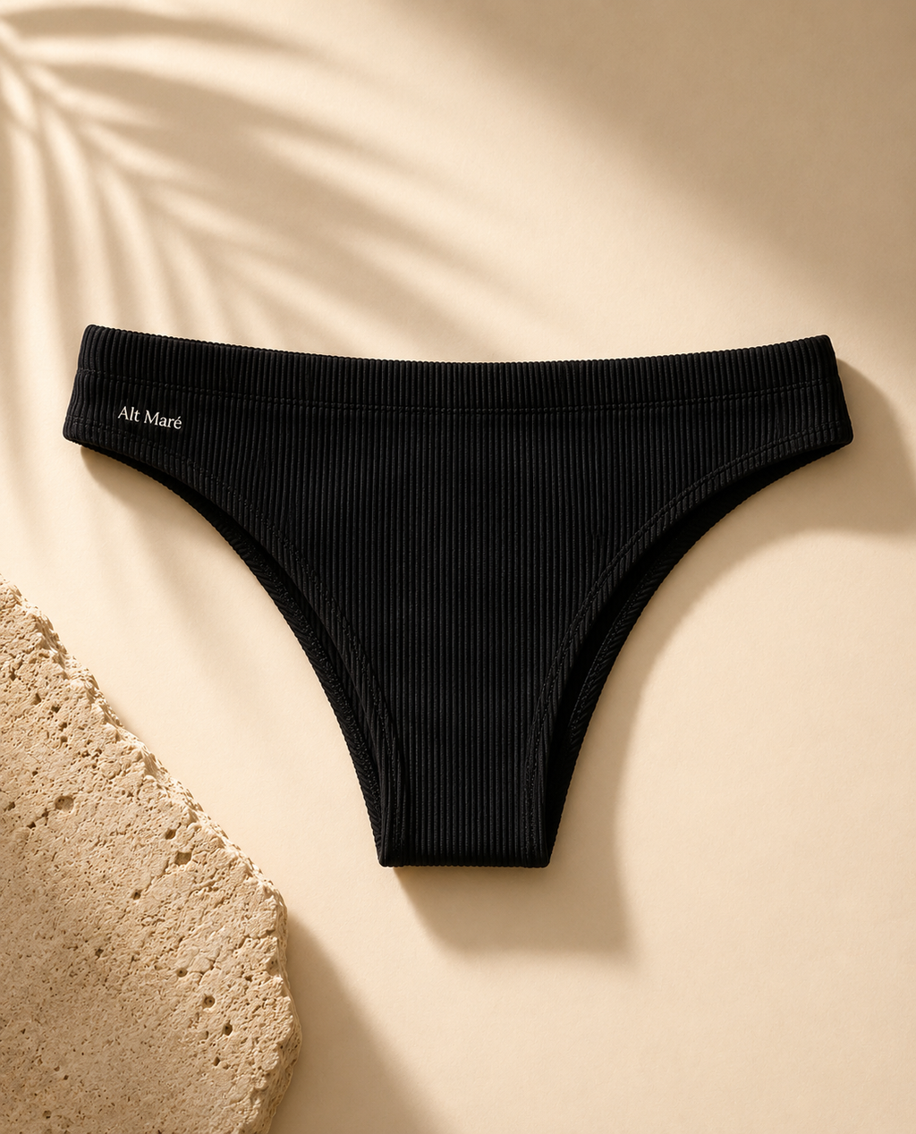 Alt Maré The Euro men's swim briefs in black, ribbed fabric, flat lay with palm shadow